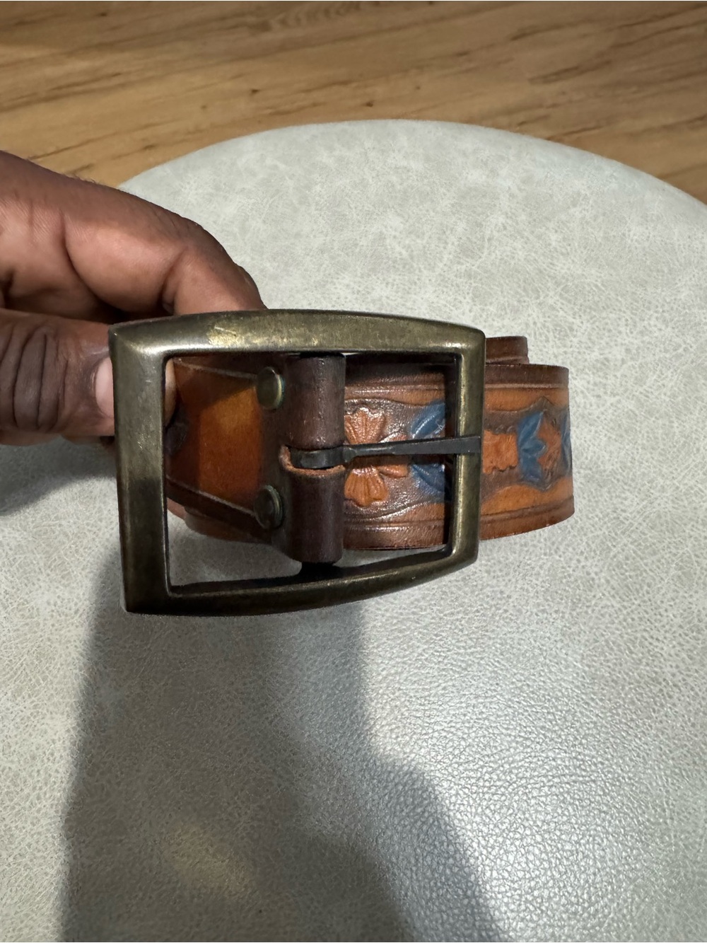 Brown leather belt with blue floral embroidery and a unique buckle